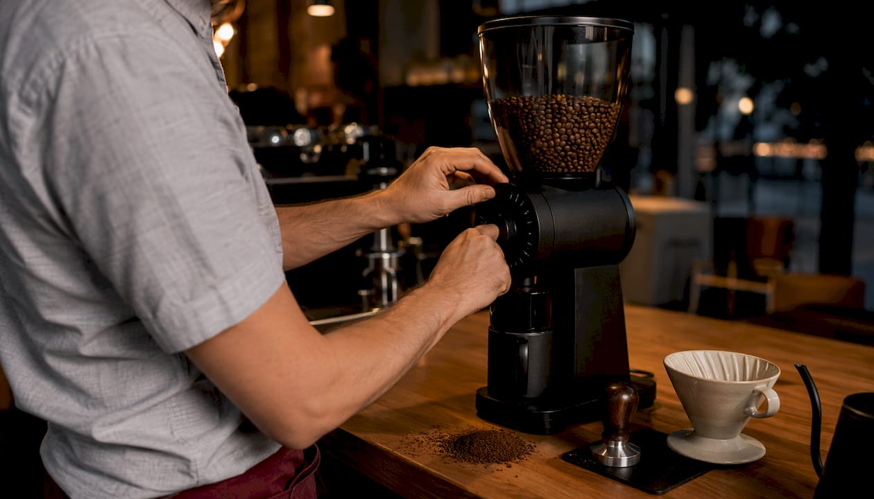 Hands adjusting burr grinder knob