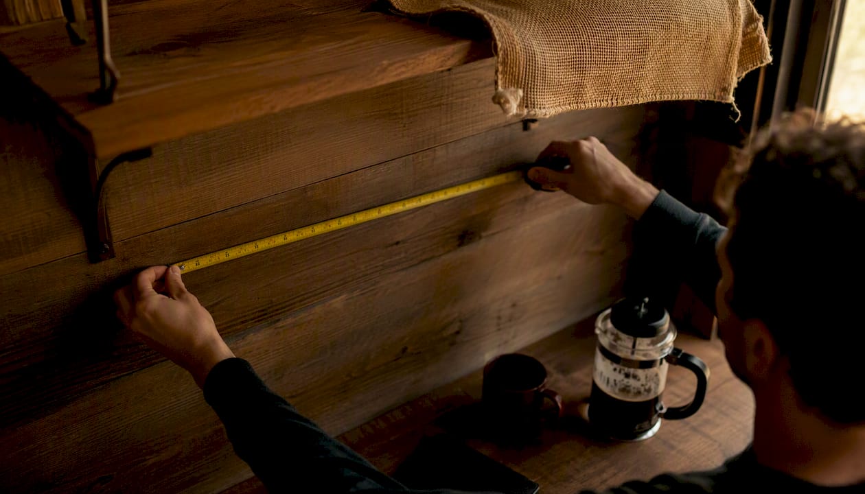 Hands measuring shelf height with tape measure