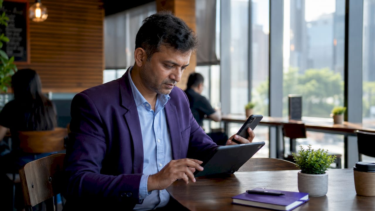 Trader using laptop and smartphone at home desk