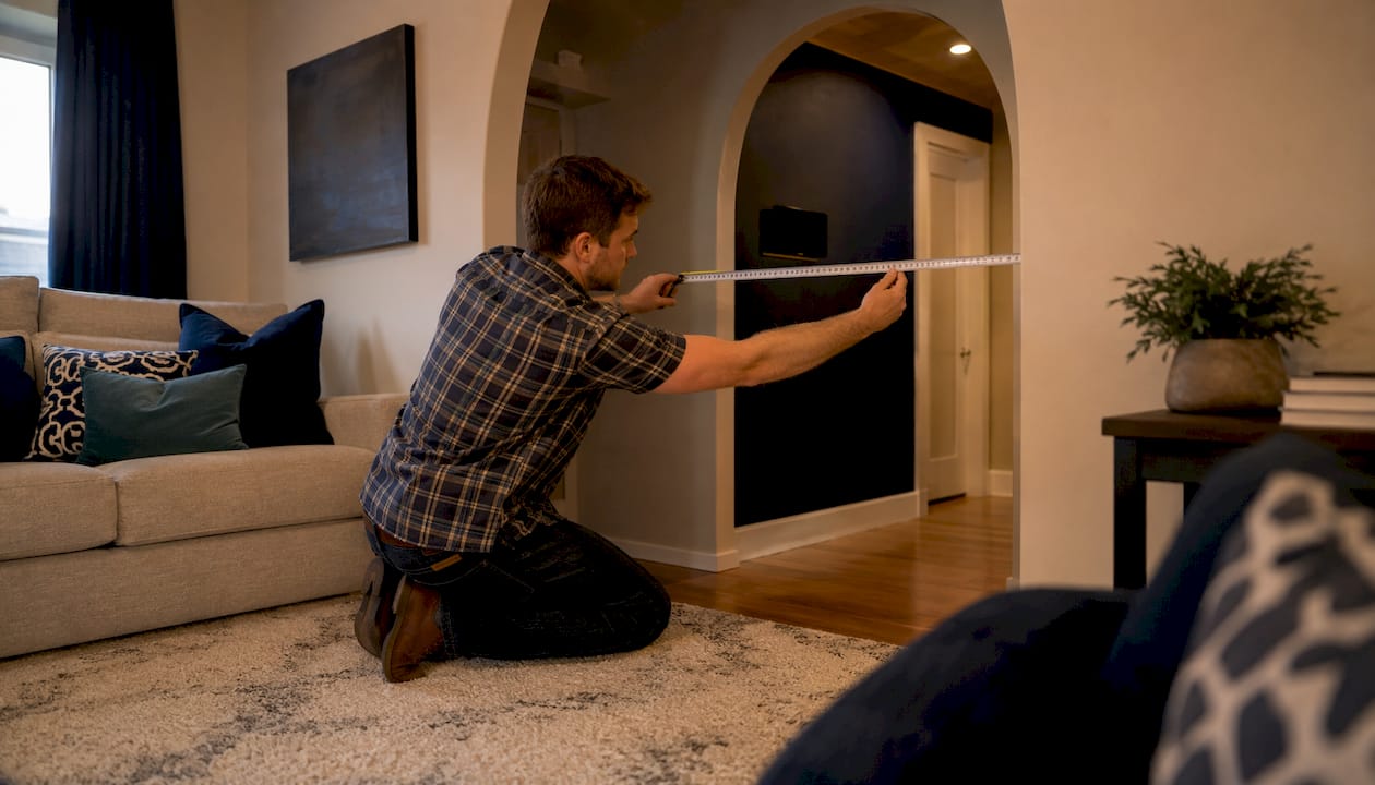 Man measuring doorway width in apartment hallway