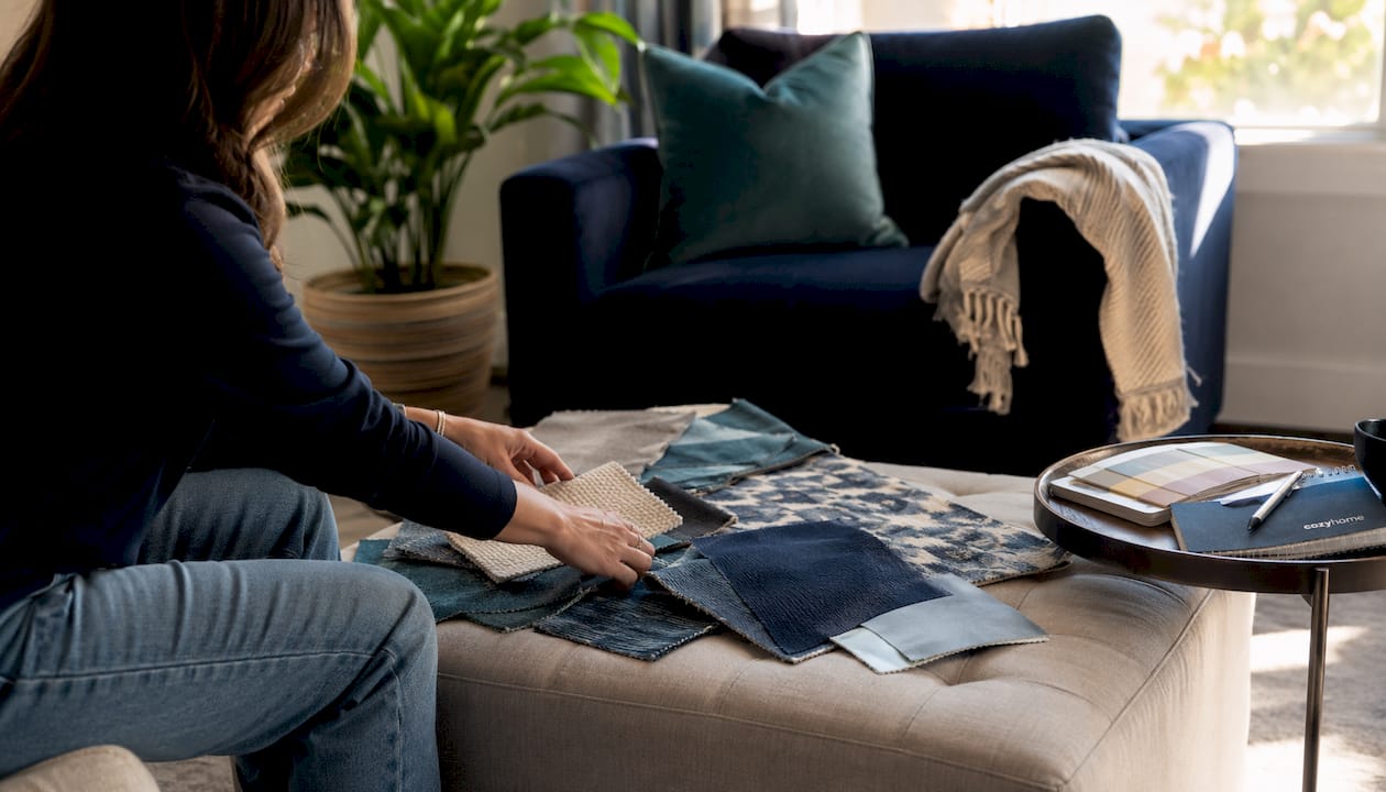 Hands examining fabric swatches on sofa frame indoors