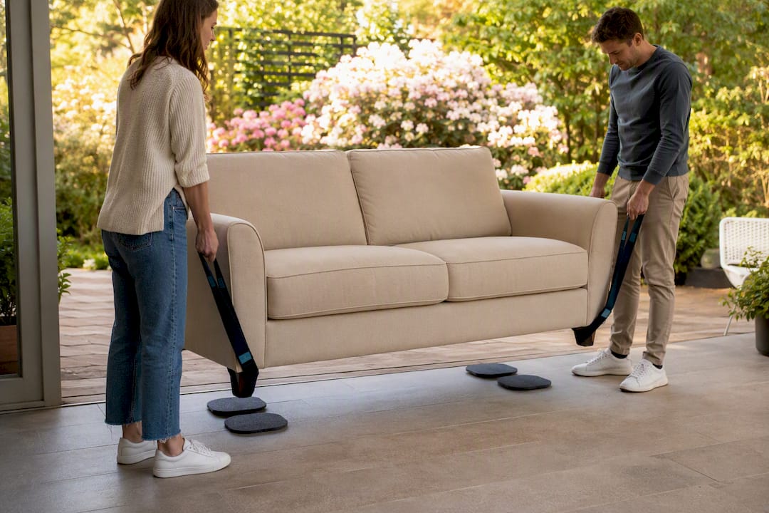 Hands using furniture sliders and lifting strap