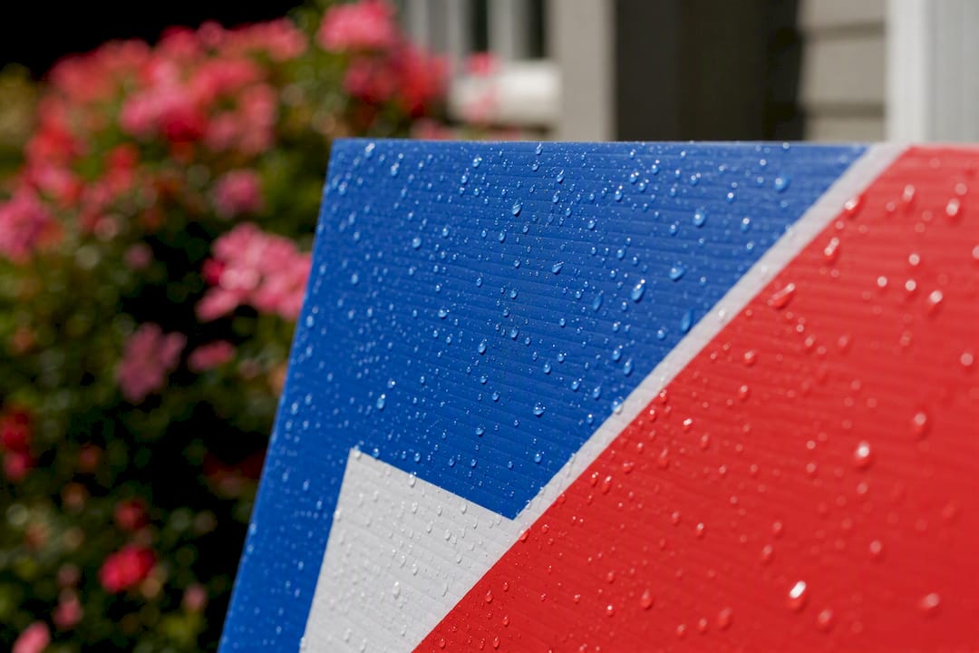 Water droplets beading on printed yard sign surface