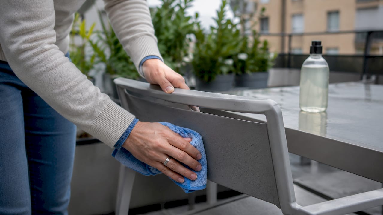 En person tvättar av en aluminiumstol ute i trädgården