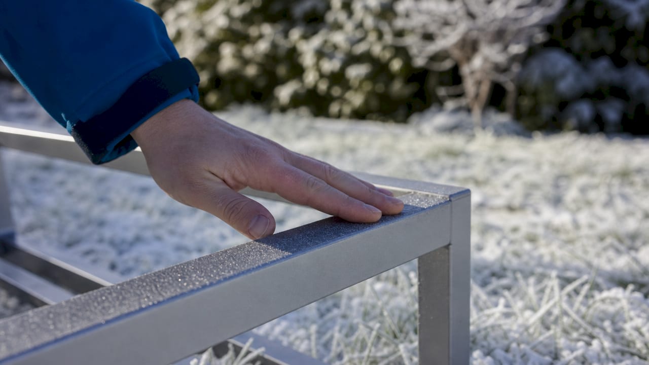 En hand som håller i en aluminiumprofil ute i kyligt väder