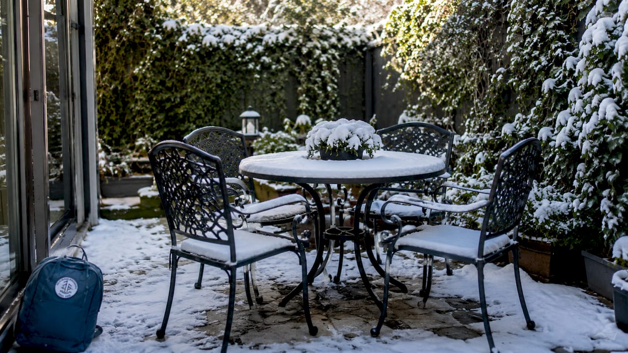 Uteplats med snötäcke och vindskydd – perfekt för en kopp kaffe även under vintern.