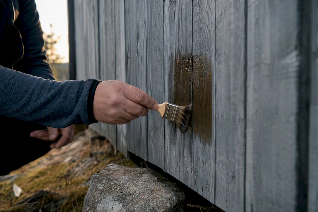 Händer som provar att applicera ett graffitskydd på en träyta
