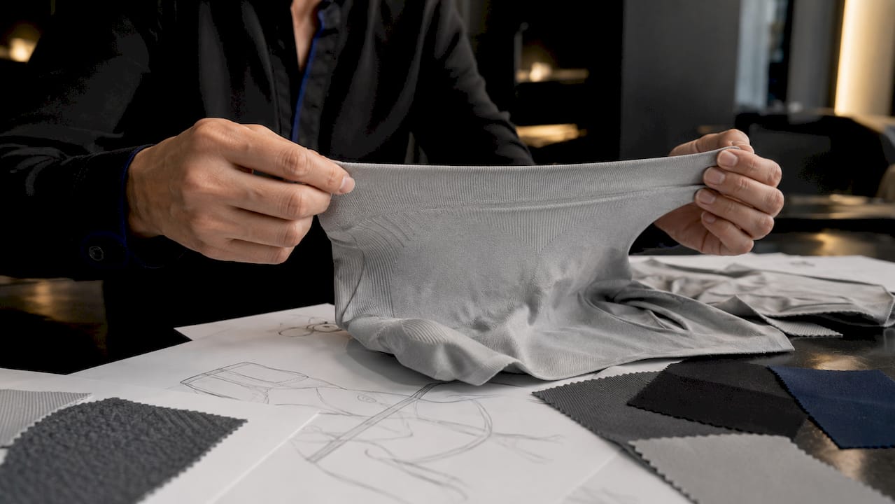Hands testing stretch on seamless shapewear fabric panel
