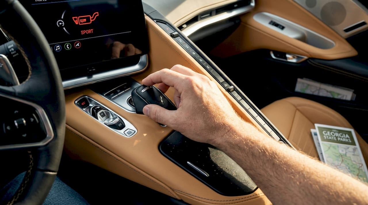 Driver changing sport exhaust mode in car