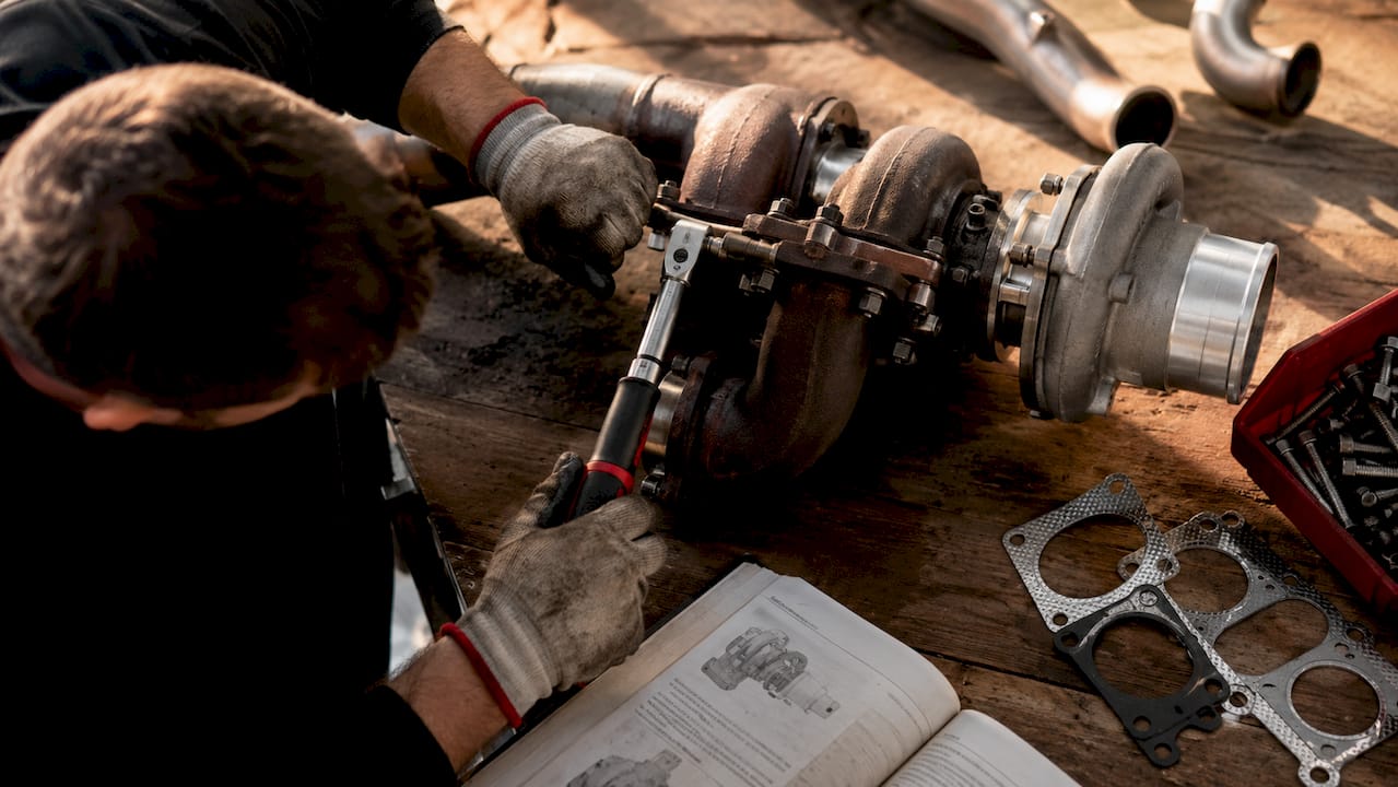 Hands tightening turbo flange bolts with torque wrench