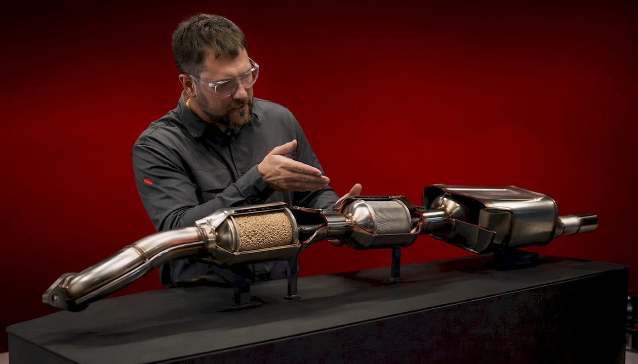 Expert explaining cutaway exhaust system model