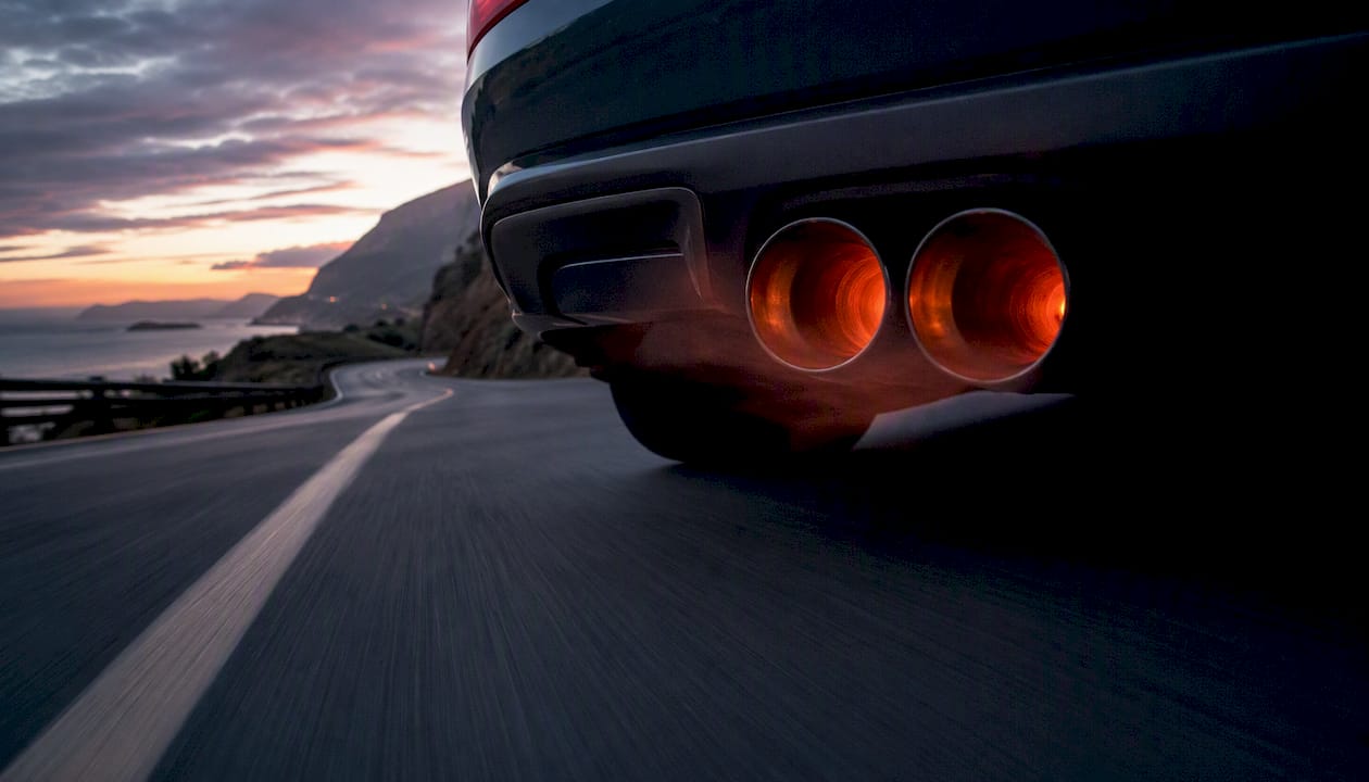 Sports car exhaust pipes on highway at sunset