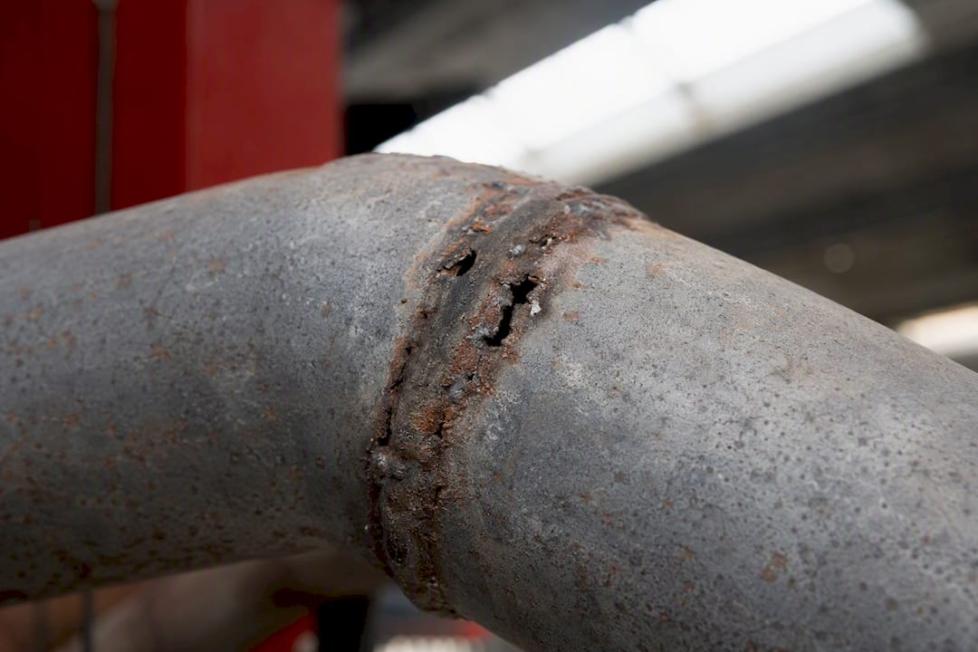 Close-up of rusted exhaust pipe with holes