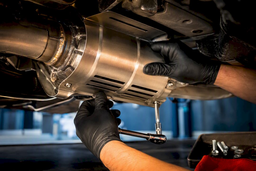 Technician fitting downpipe heat shield