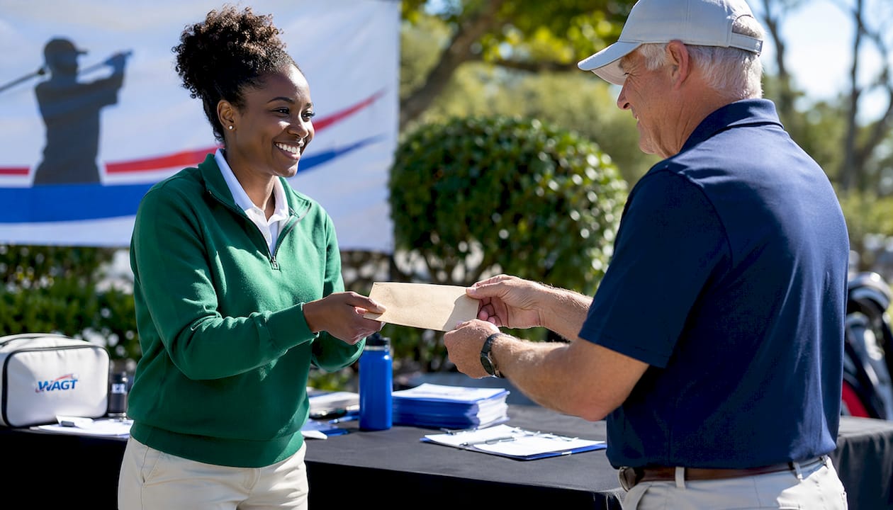 Hands exchanging golf tournament entry fee envelope