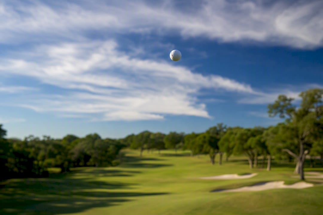 Golf ball flying high over windy fairway