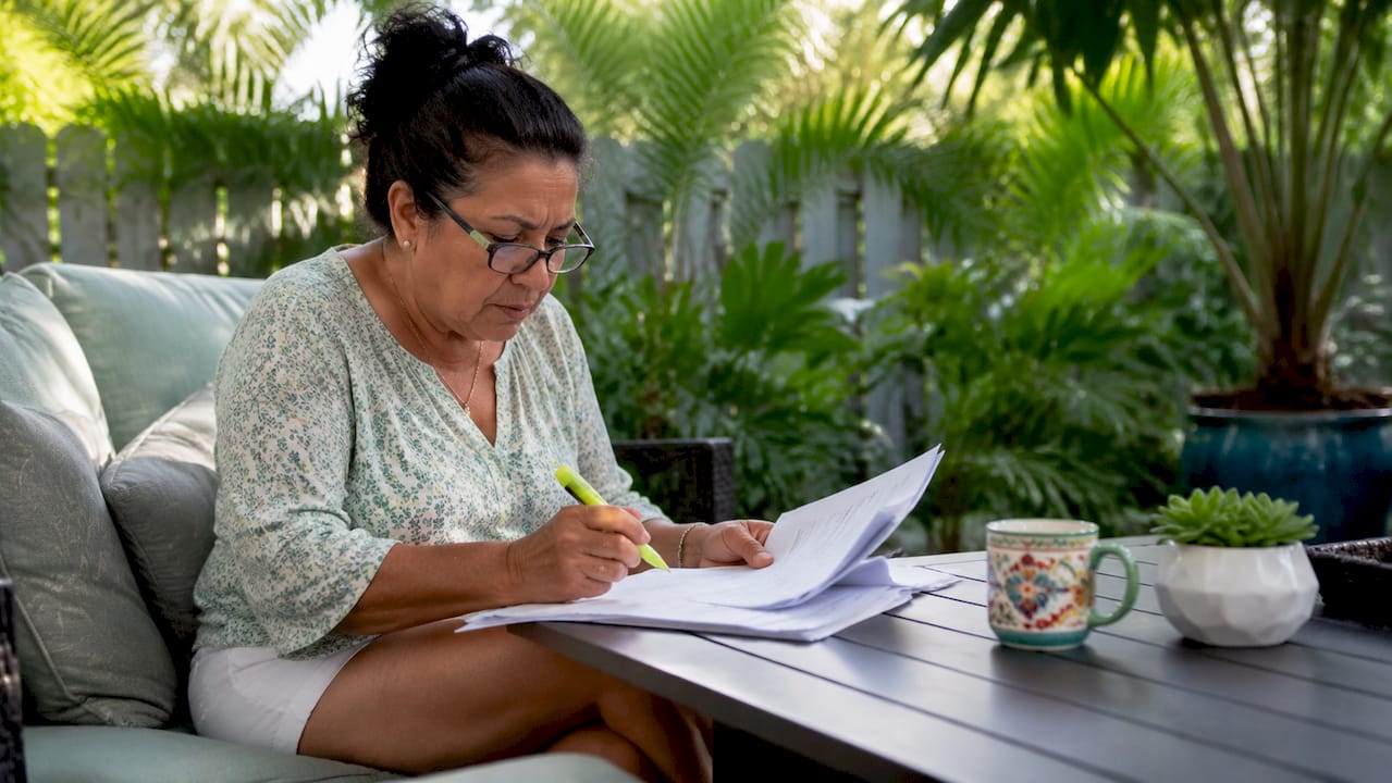 Homeowner reviewing roofing permit papers at kitchen table