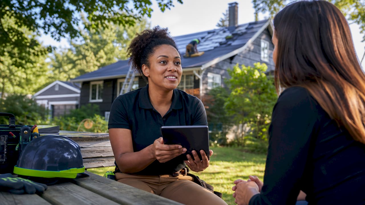 Contractor explaining roof financing options outdoors