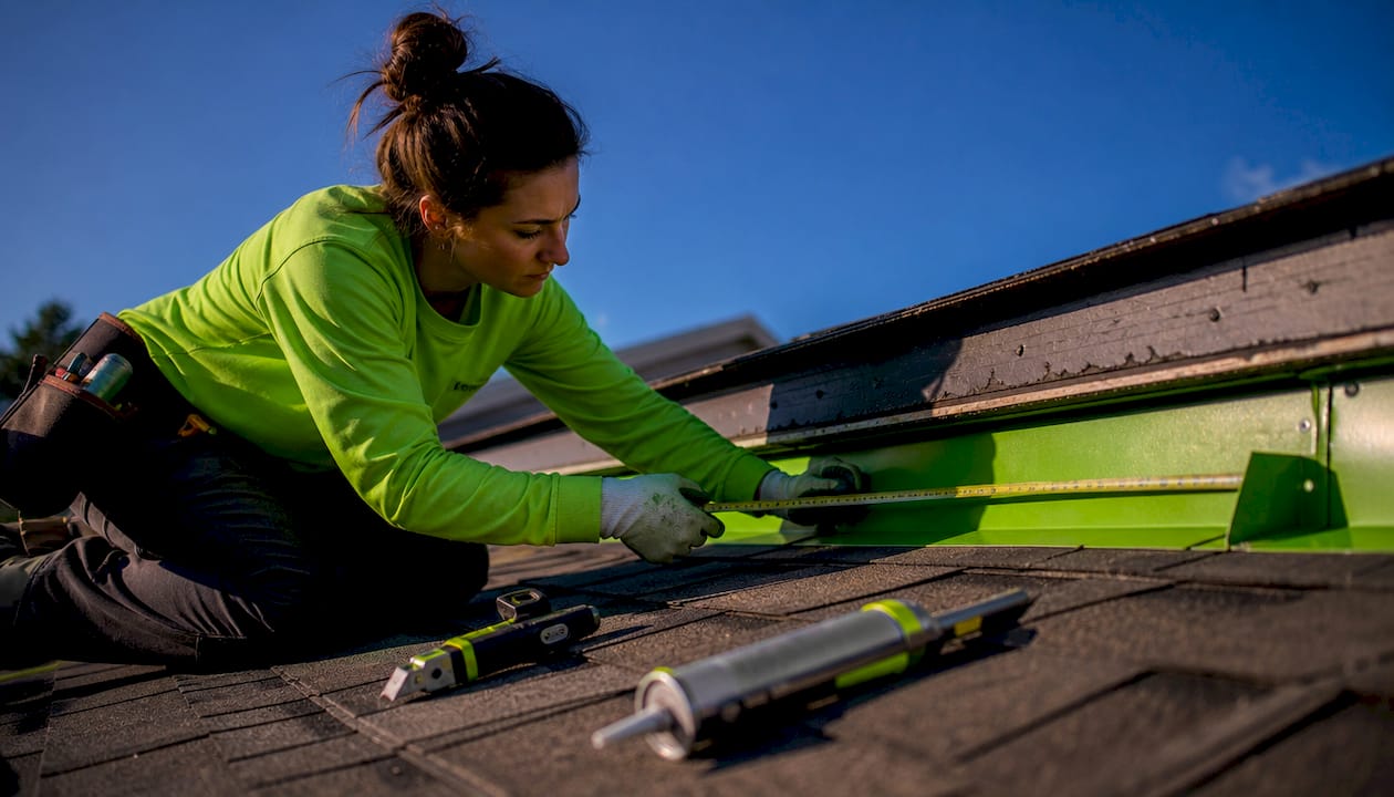 Technician measuring roof flashing on flat roof