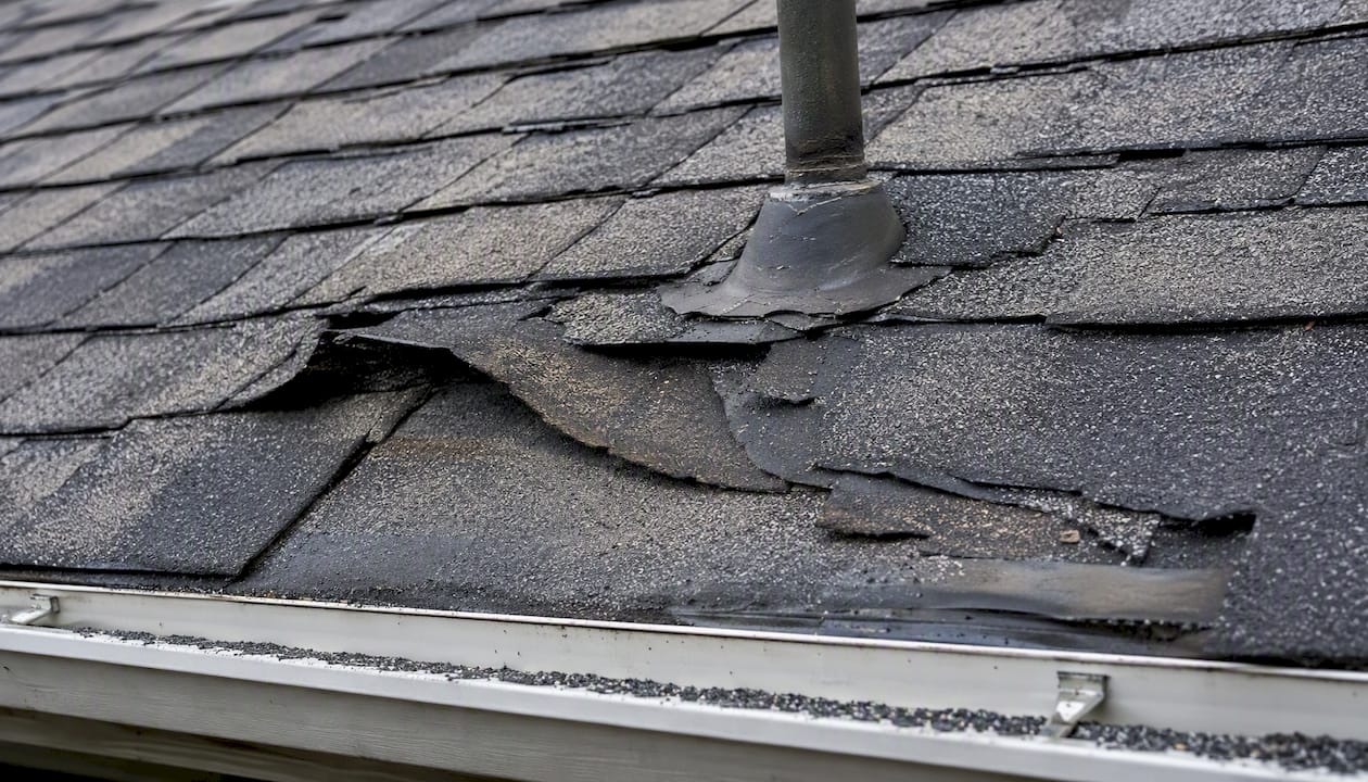 Close-up of lifted and missing roof shingles