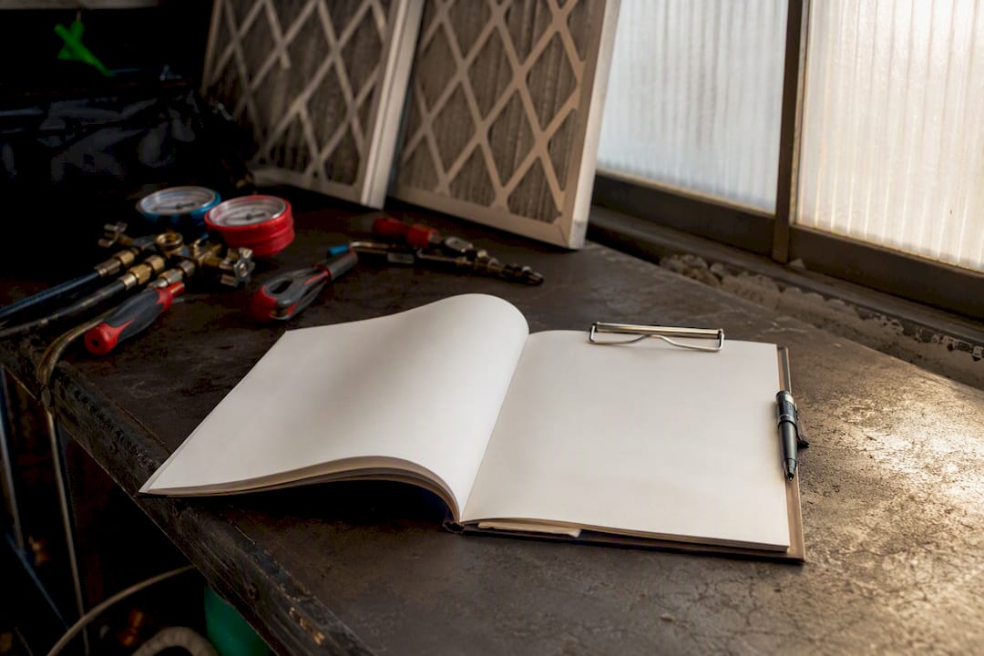 Blank HVAC maintenance service logbook on clipboard by equipment