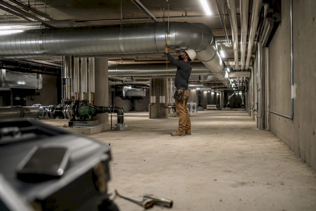 Tradesperson measuring commercial HVAC duct diameter