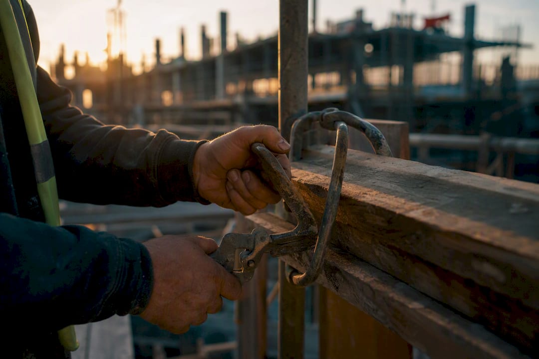 Hands releasing retention clamp on scaffolding