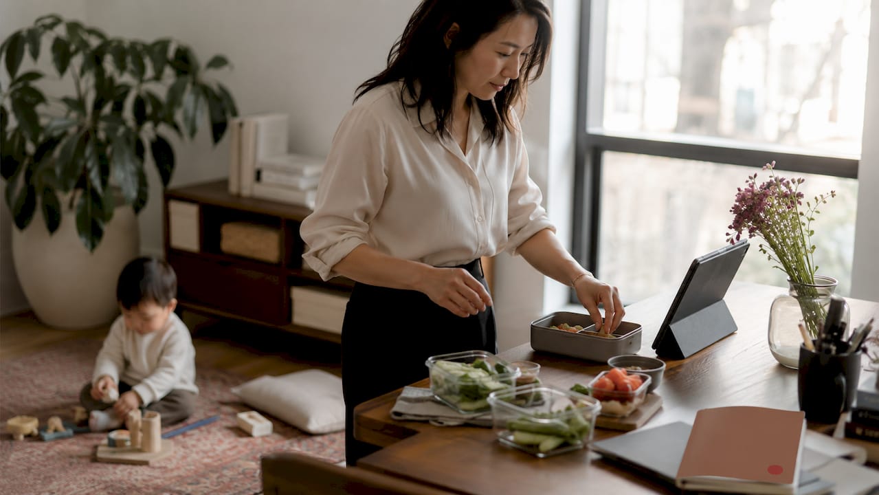 Woman multitasking work and family care in kitchen