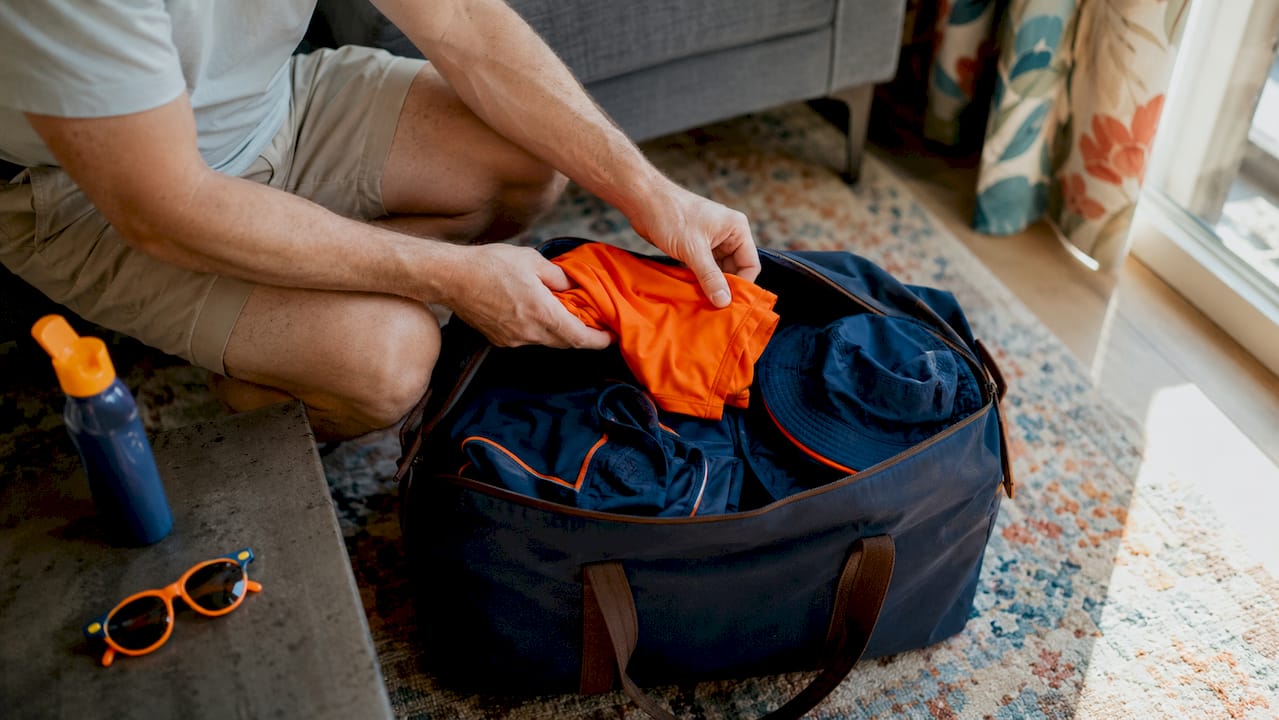 Hands packing UV protective clothes into a bag