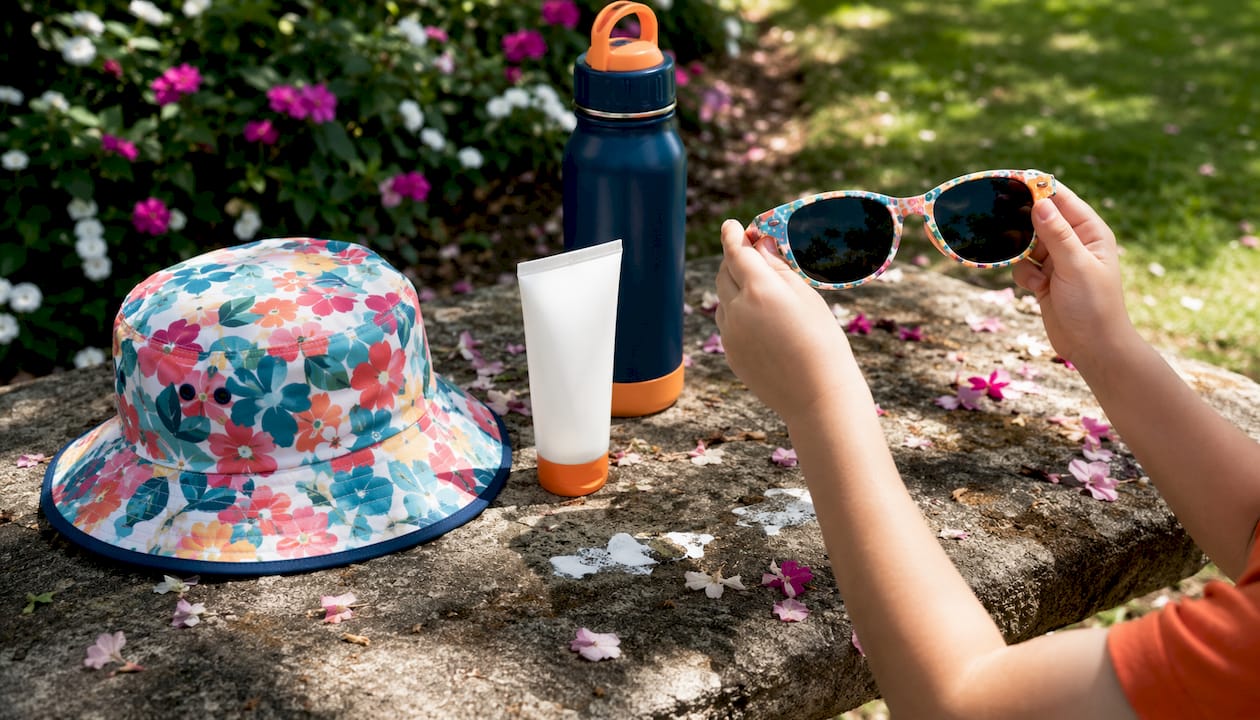 Child’s sunglasses, hat, and sunscreen on table