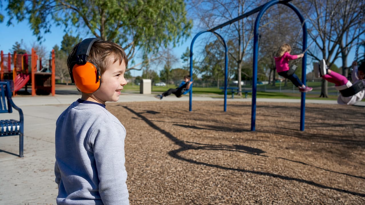 Child outdoors wearing hearing protection earmuffs