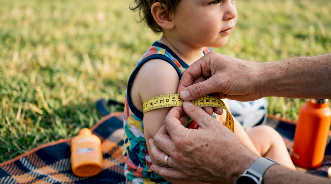 Person measuring arm circumference with tape