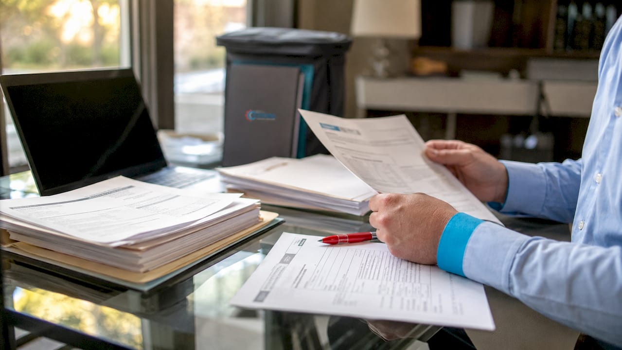 Hands reviewing HVAC contractor documents on desk