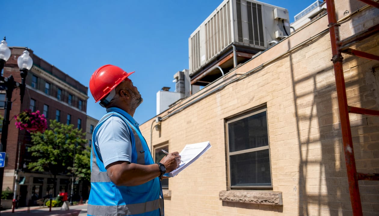 Building inspector examining rooftop HVAC unit
