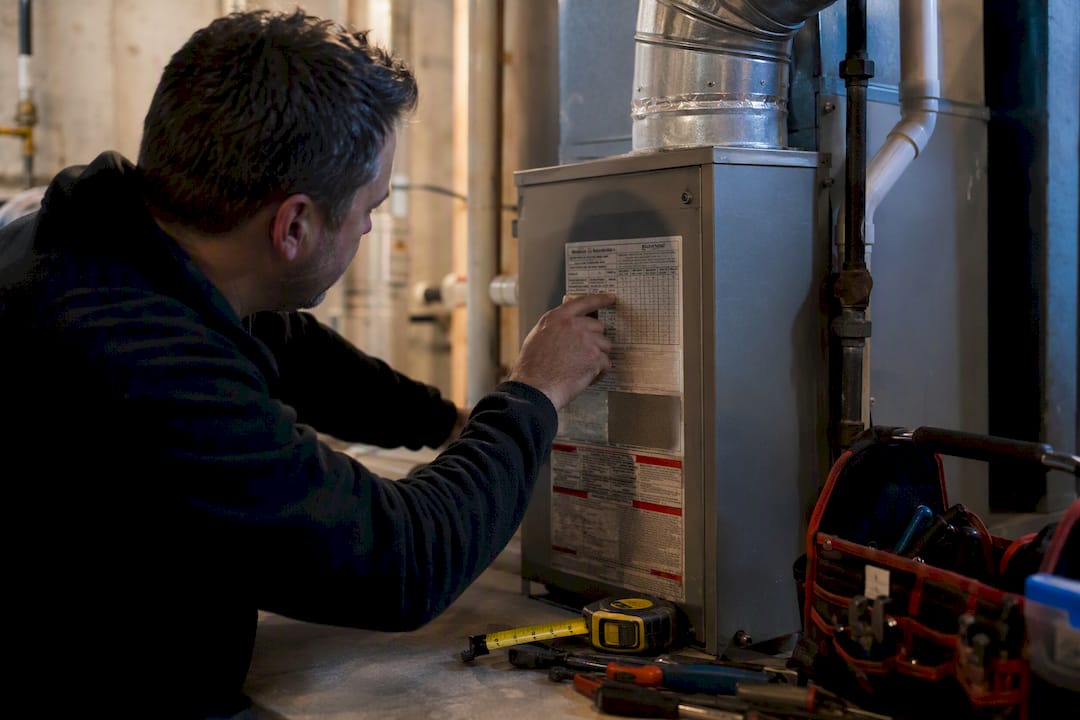 Technician hands inspecting furnace data plate