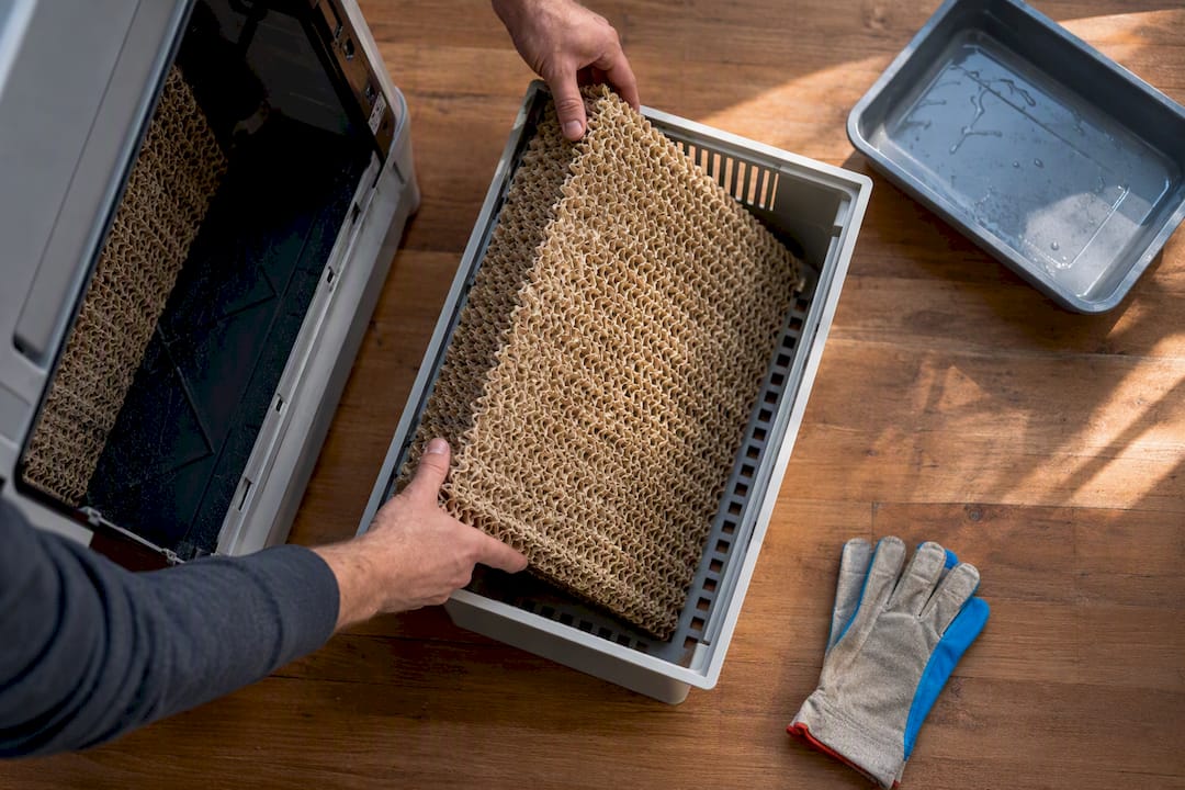 Hands removing evaporative cooler pad