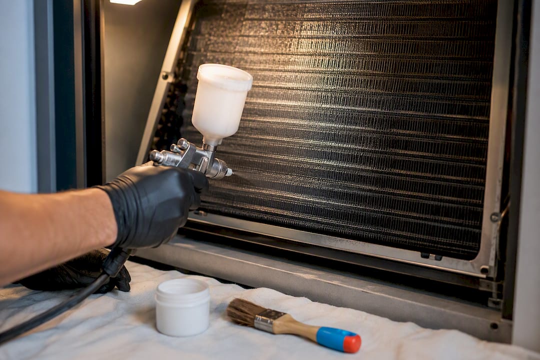 Technician applying coating to evaporator coil