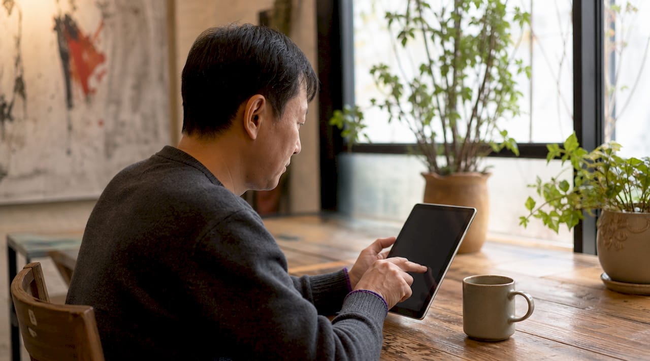 Close-up of hands navigating mental health directory on tablet in library