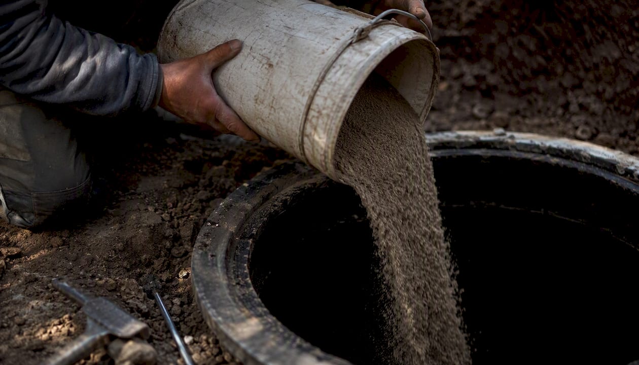 Hands pouring sand into oil tank during decommissioning