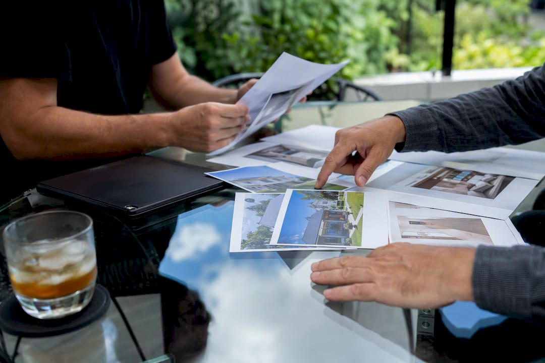 Hands arranging real estate deal documents on table