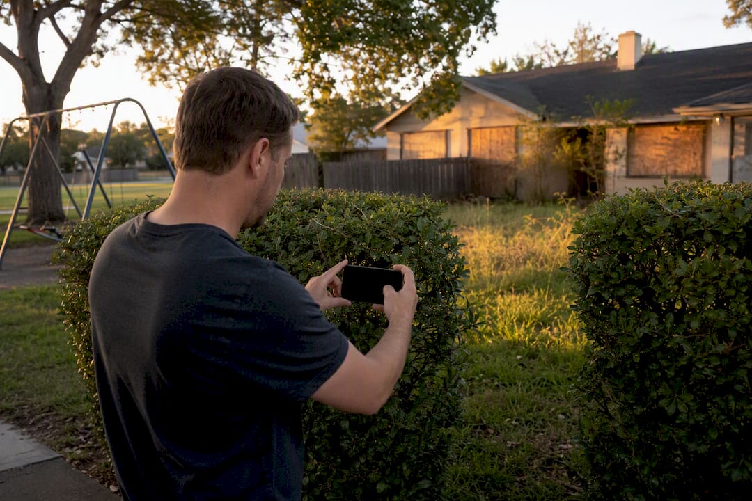 Investor photographing distressed property exterior
