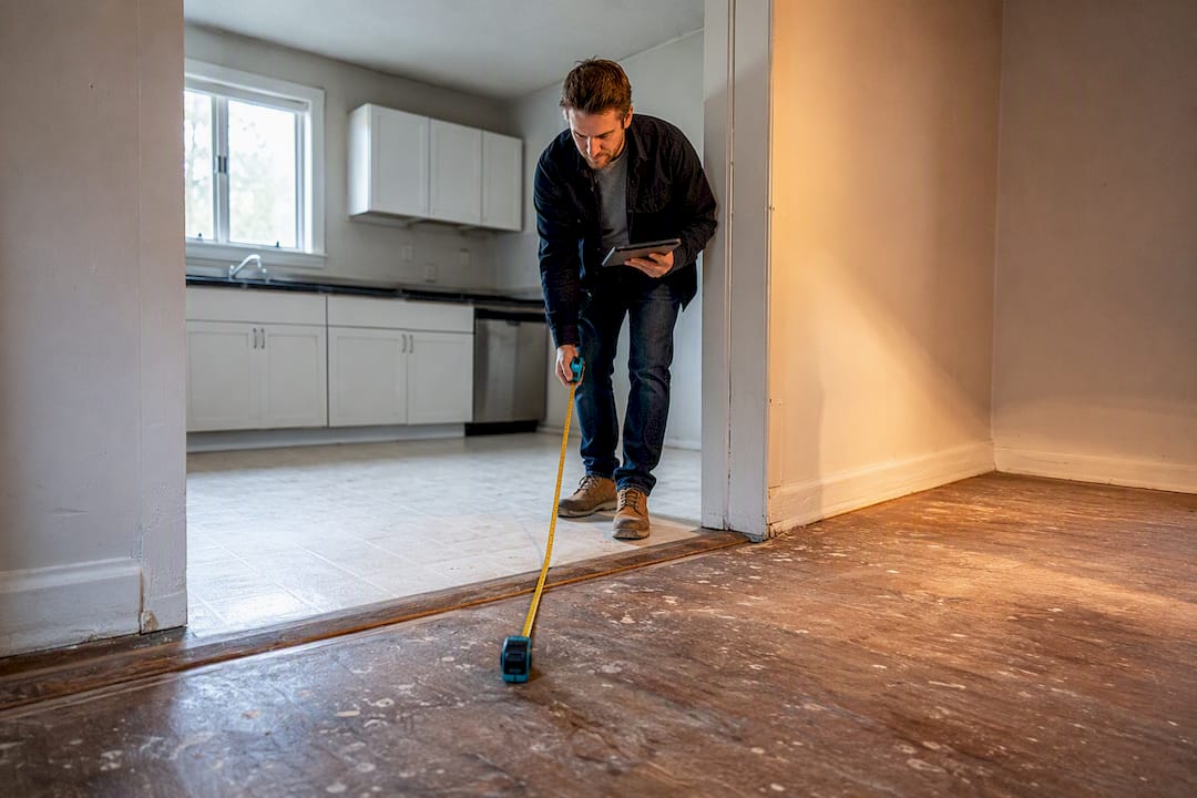 Investor measuring vacant home floor area