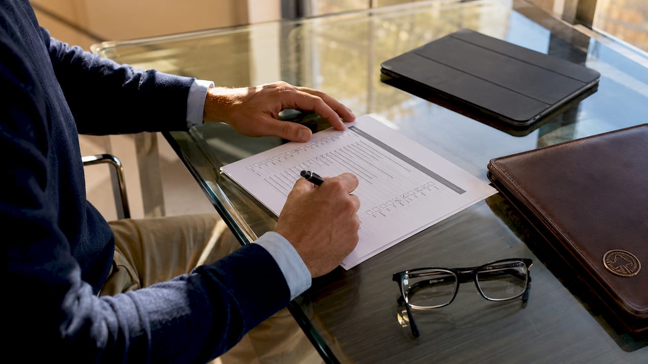 Hands marking loan underwriting checklist