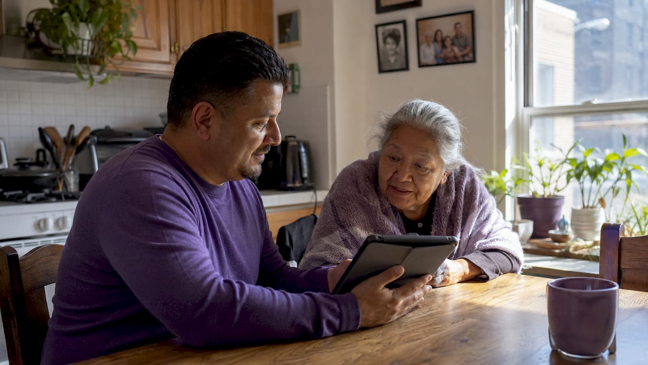 Man and elderly mother reviewing care provider options on tablet