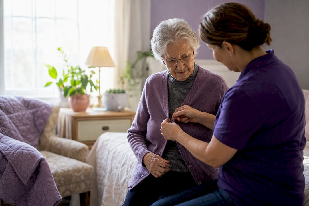 Caregiver helping elderly person with sweater