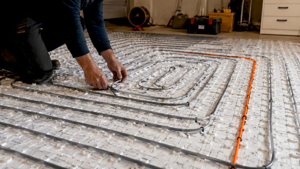 Pose d’un tube sur l’isolant lors de l’installation d’un chauffage au sol