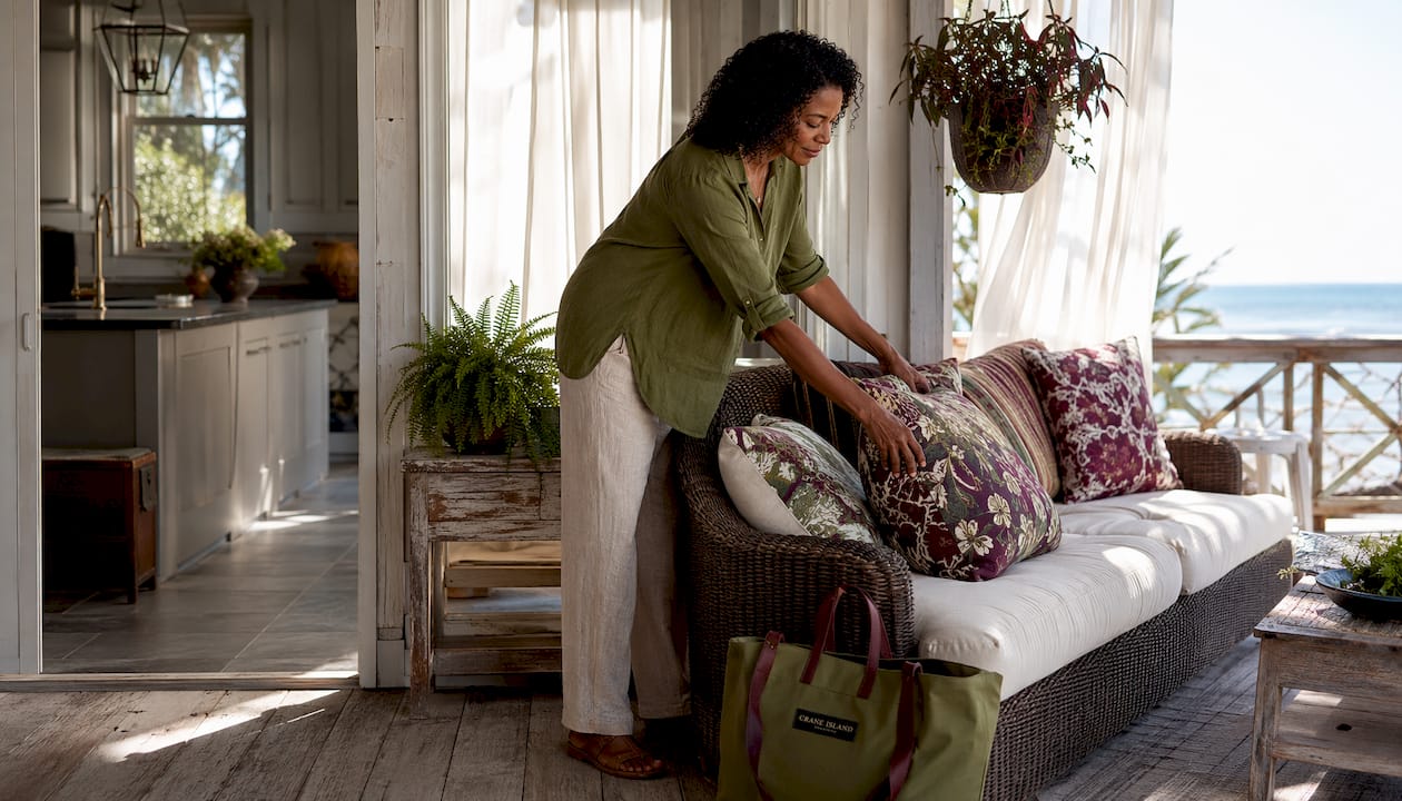 Woman arranging cushions on coastal porch sofa