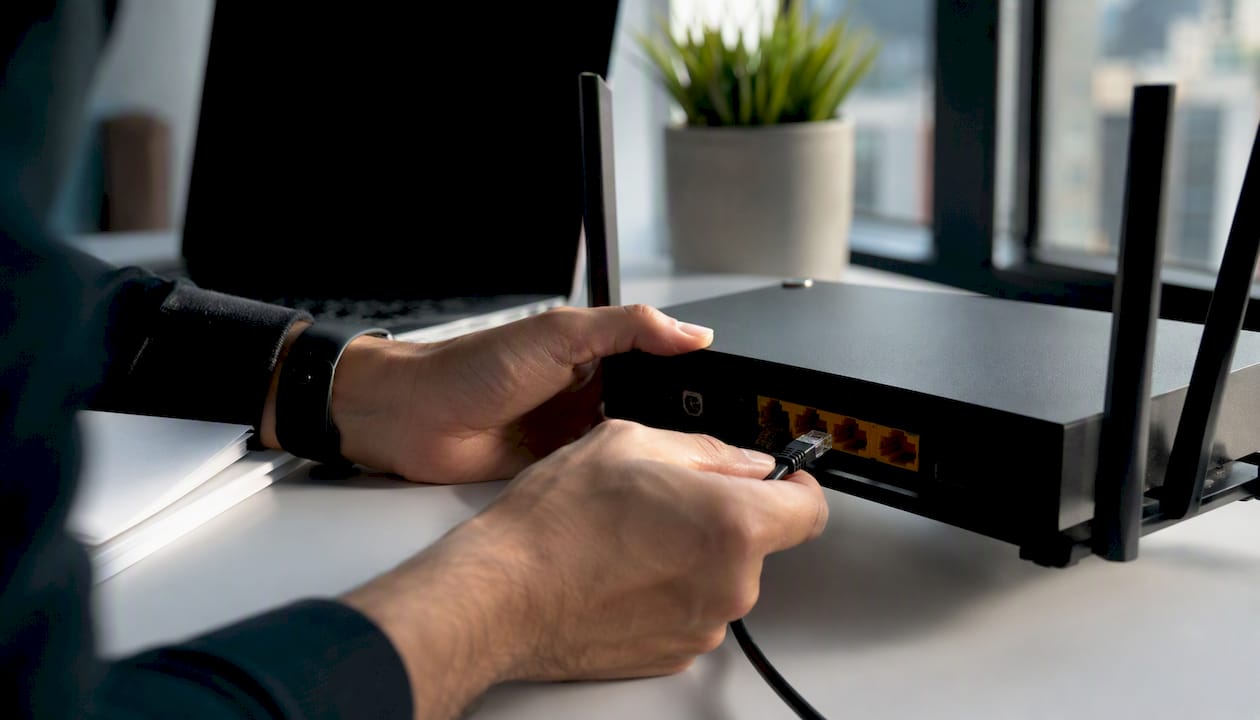 Hands plugging network cable into router