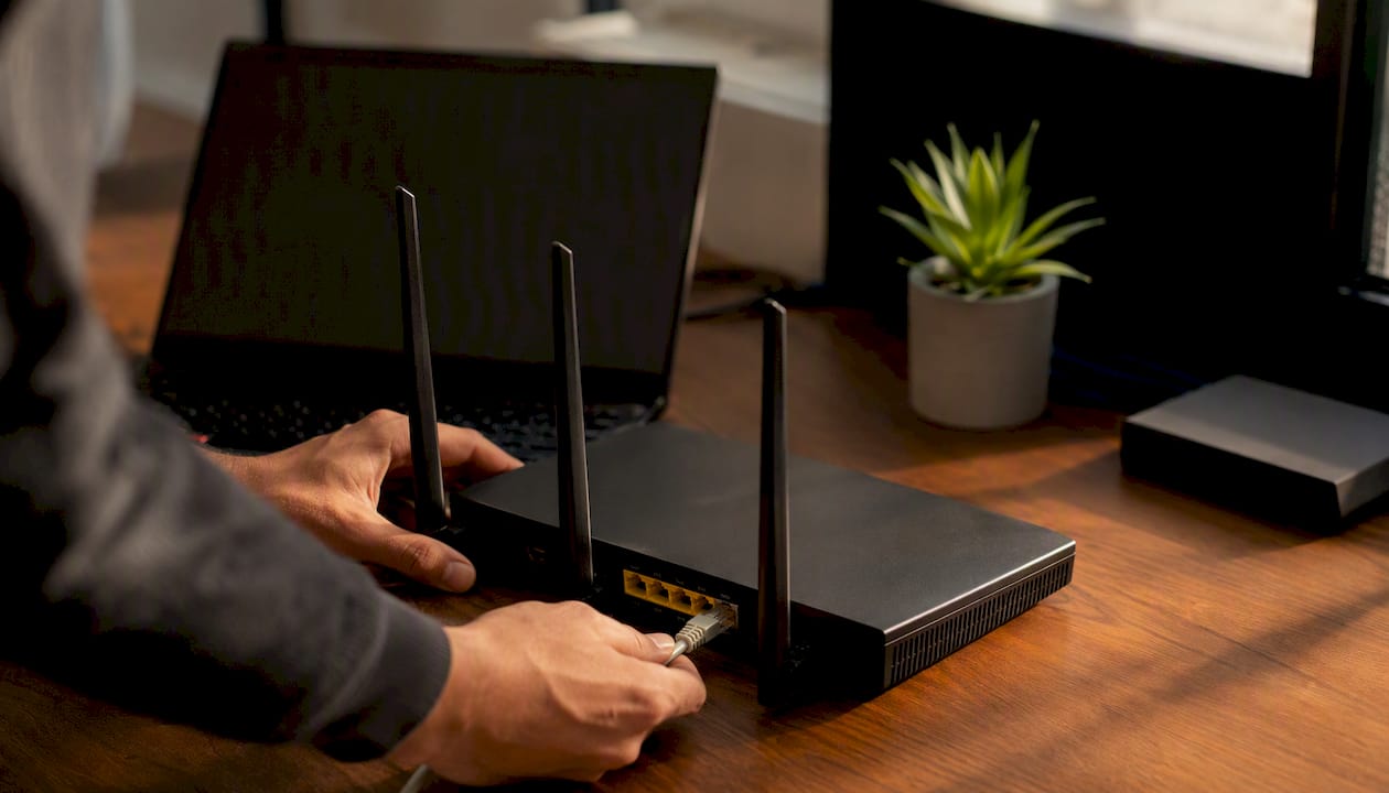 Hands plugging network cable into router