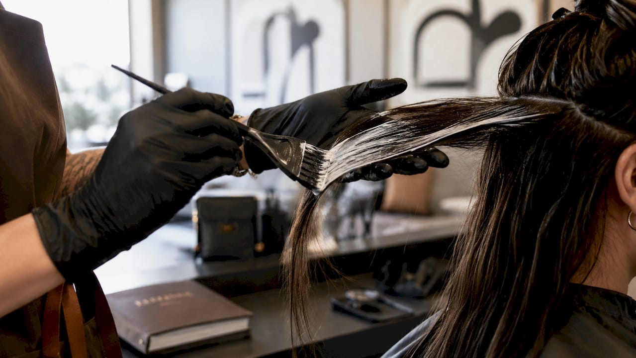 Close-up of hands painting hair balayage technique